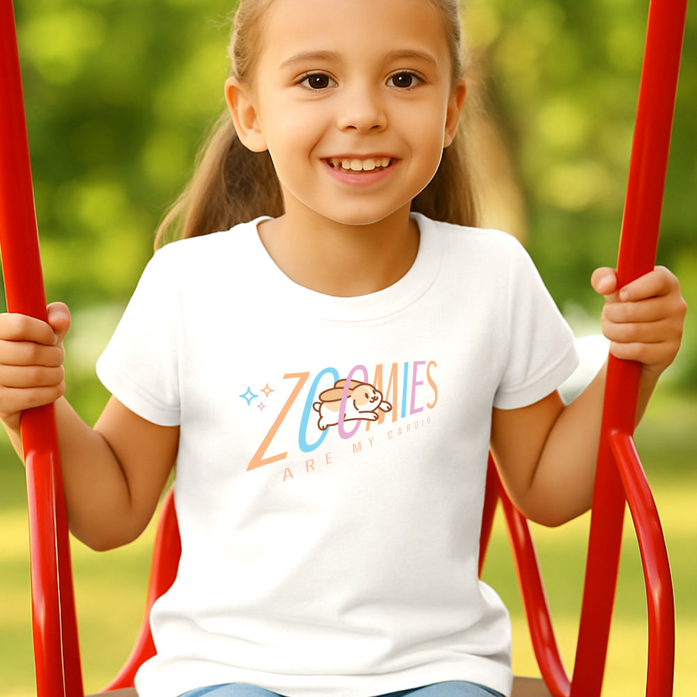 Child wearing a white t-shirt with 'Zoomies are my Cardio' logo on a red swing