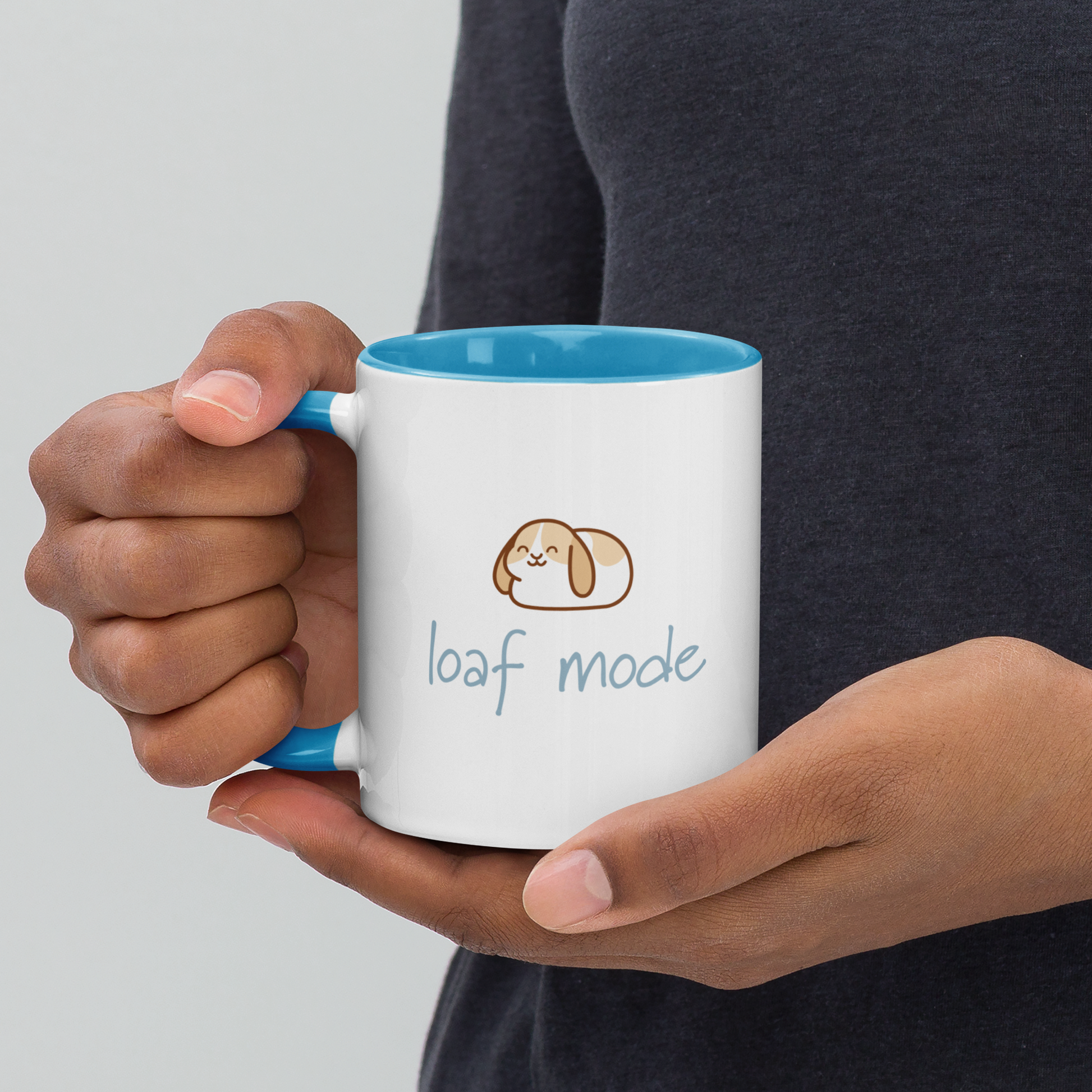 Person holding a mug with 'loaf mode' text and a dog illustration on a plain background