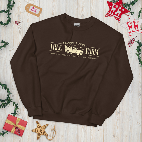 Brown sweatshirt with 'Floppy Loppy Tree Farm' text on a wooden surface with Christmas decorations.